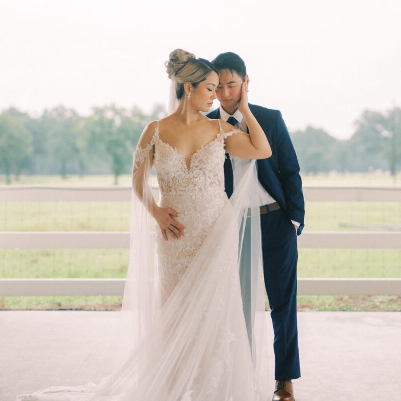 A portrait of the bride and groom set against a ranch field backdrop.