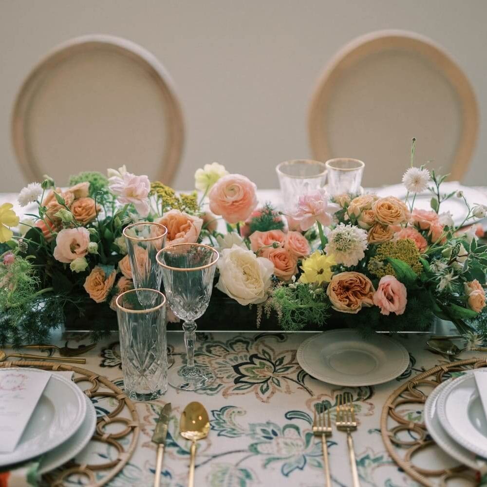 A table setting with a long flower arrangement as a centerpiece.