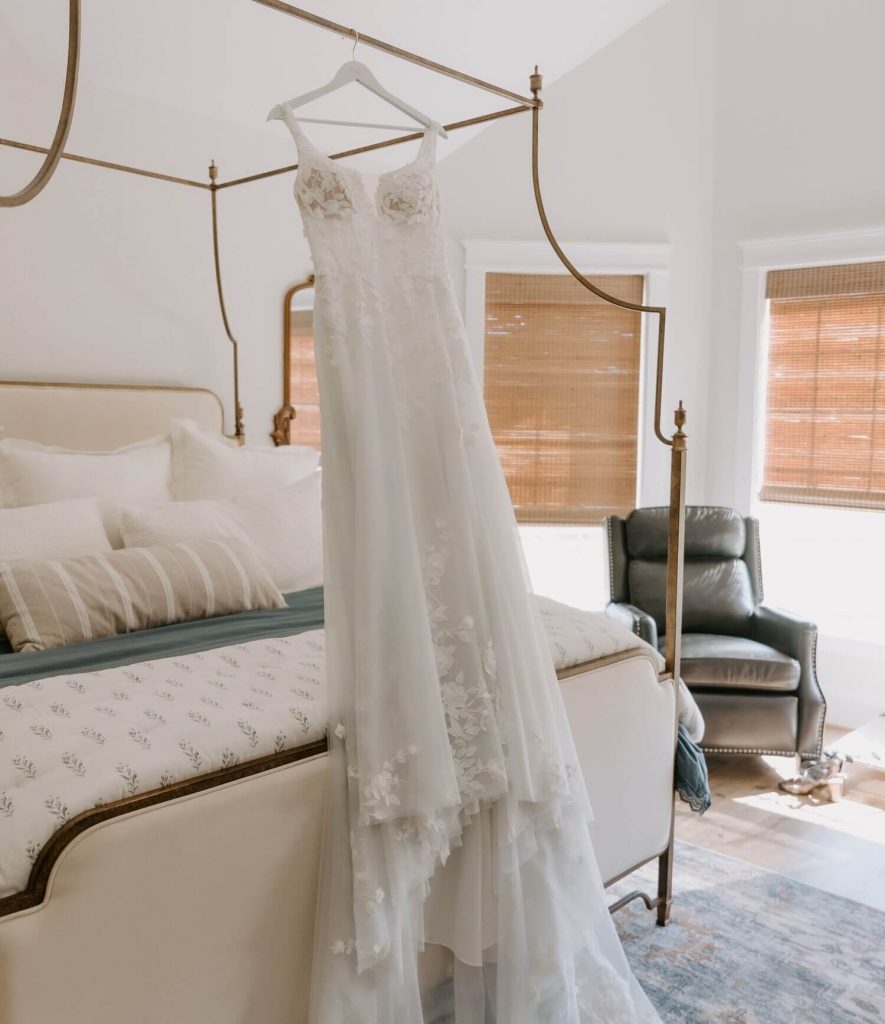 A lace wedding dress hung on the bed frame.