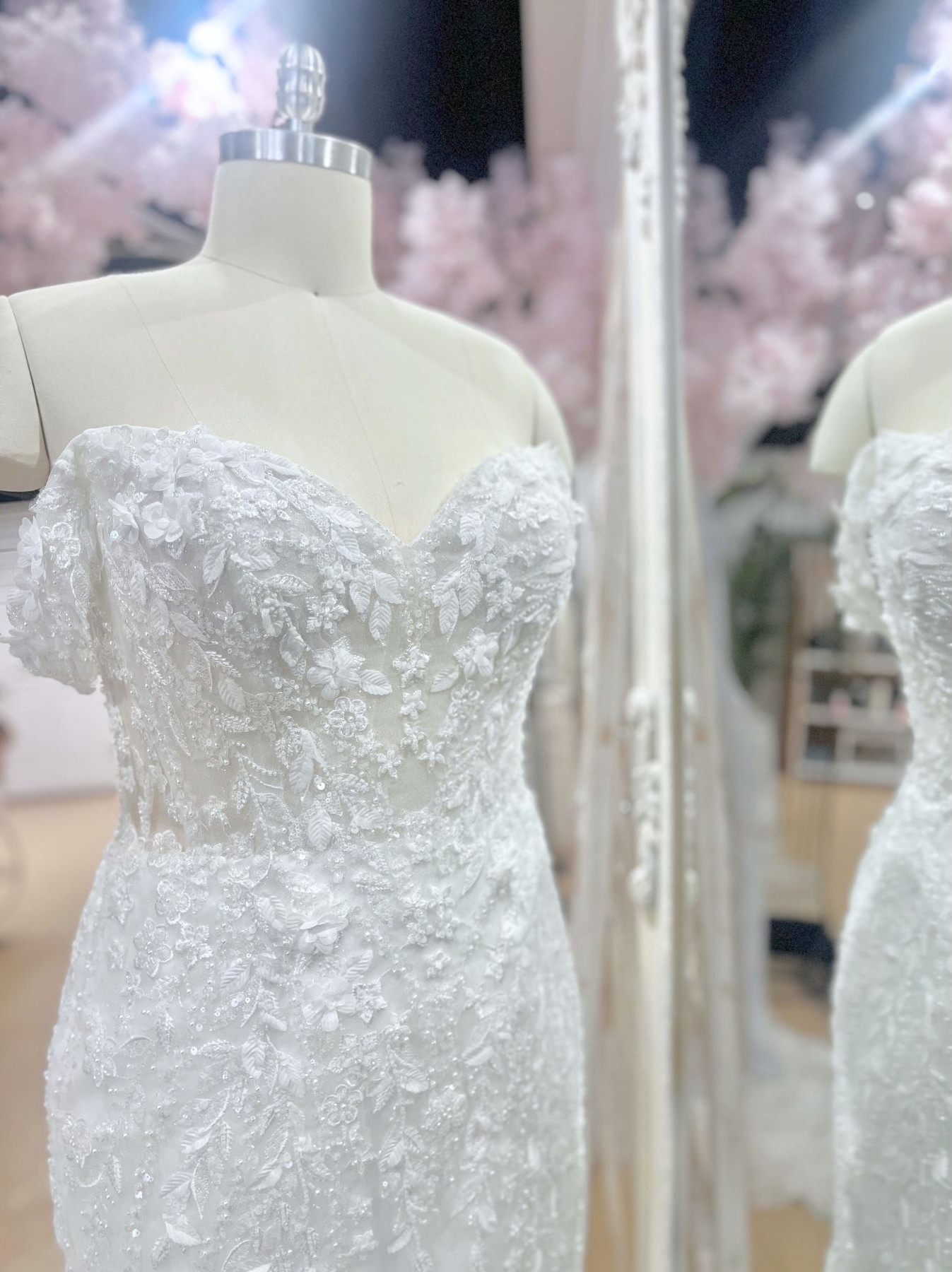 Strapless, form-fitting wedding gown covered in shimmering sequins and lace embellishments on a mannequin.
