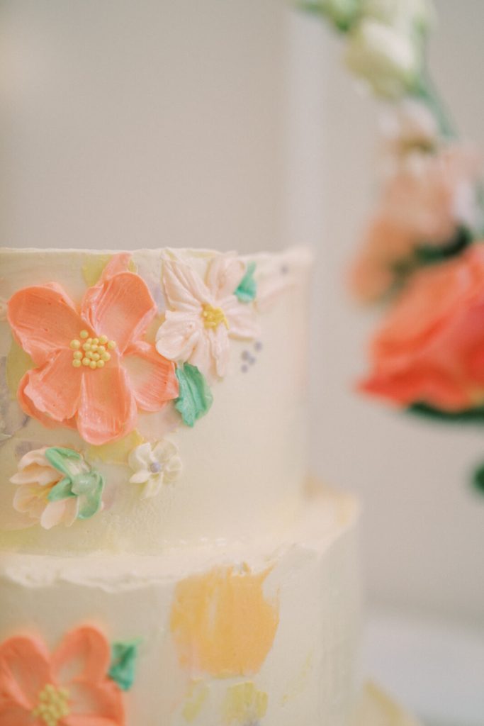 A beautiful cake with white frosting and orange flower decorations.