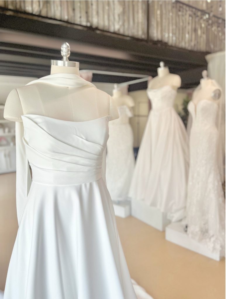 Collection of elegant white and ivory wedding gowns hanging on a rack.
