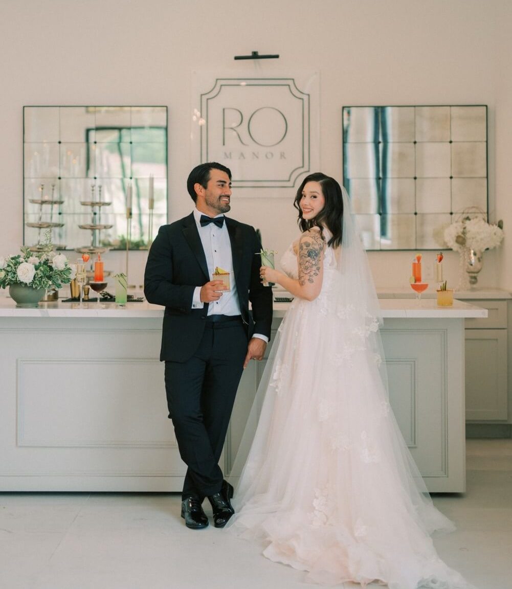 A groom and bride enjoying each other's company by the cocktail booth at their wedding venue.