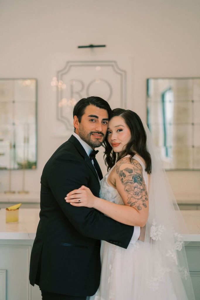 A portrait of a groom and bride holding on to each other with their heads leaning.