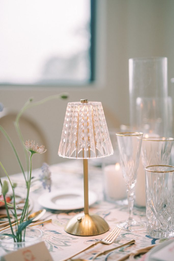 A lamp as a table centerpiece is lined up with a few glasses.