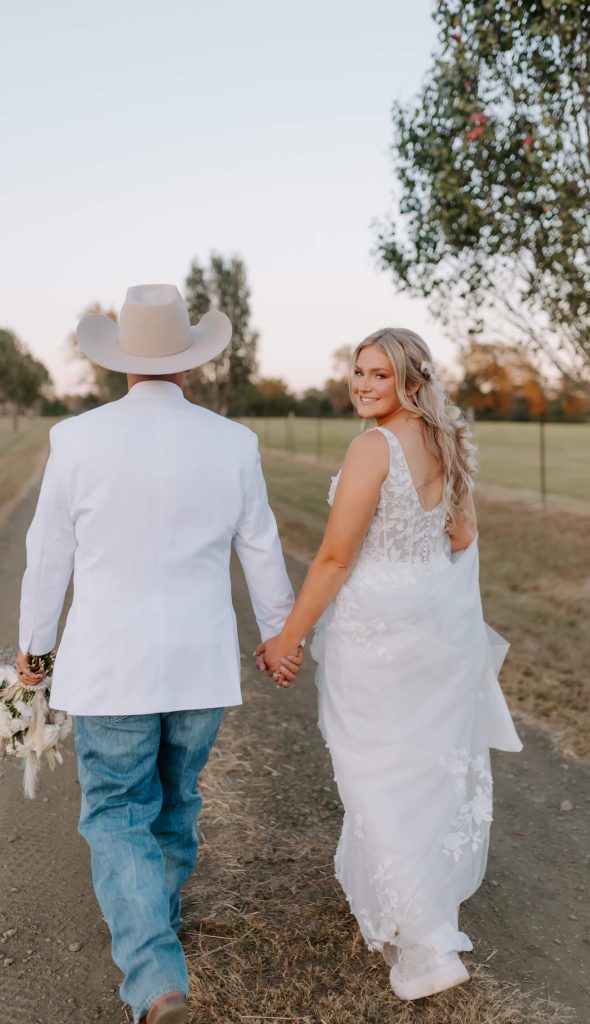 A bride and groom walking along a soil pathway.